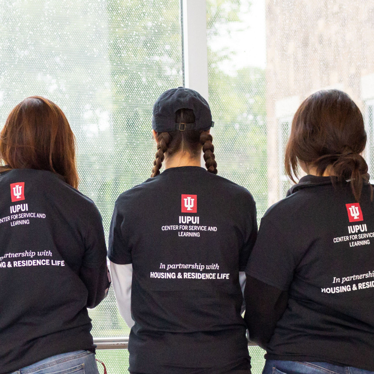 Three girls with their backs to the camera with shirts that say IUPUI Center for Service and Learning