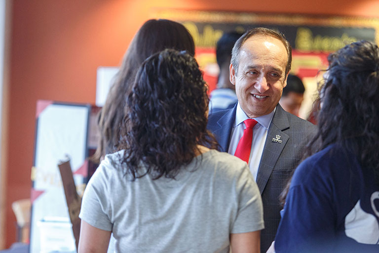 Chancellor Paydar smiling while speaking with two students