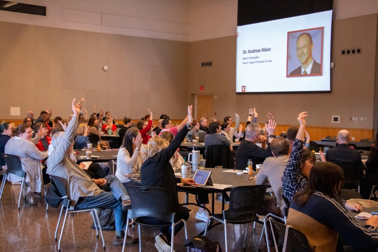 Tables of IUPUI staff raising their hands during a presentation