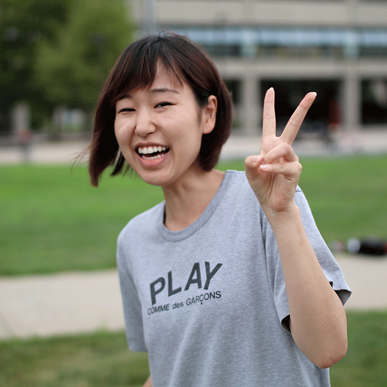 A photo of a student smiling and flashing a peace sign.